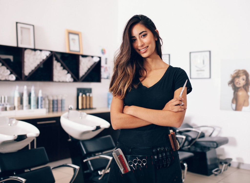 Hair stylist in black standing in front of sinks in a salon - How to Open a Hair Salon: A Complete Guide - Lunica Beauty