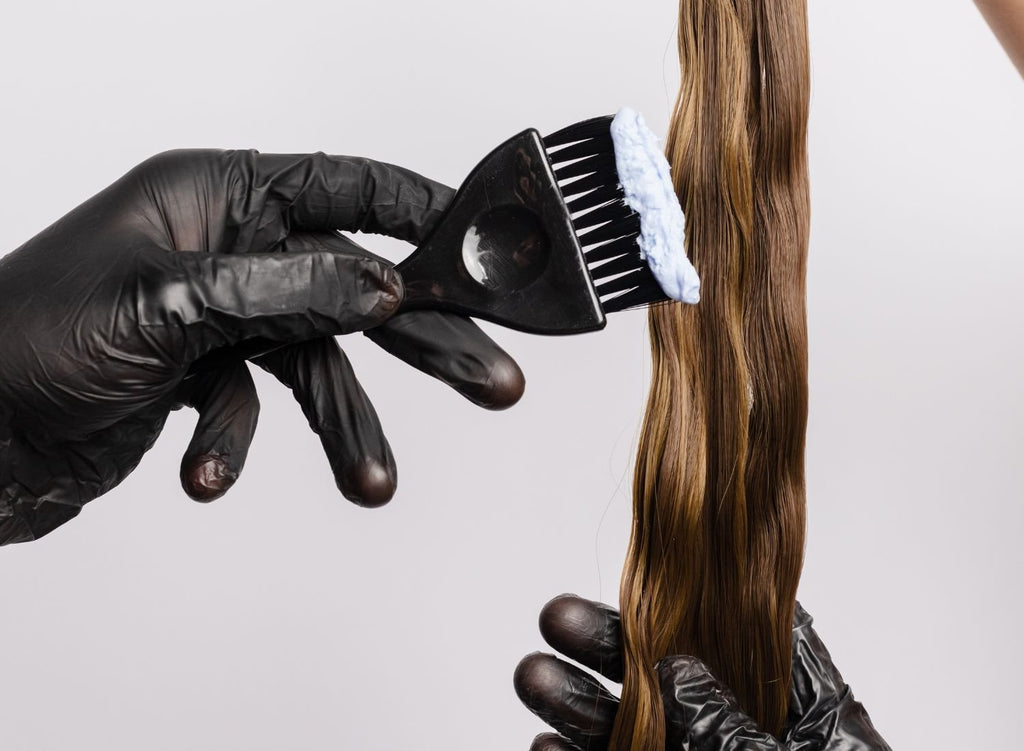 technician applying hair dye to a strand of brown hair - Most Popular Salon Services - Lunica Beauty